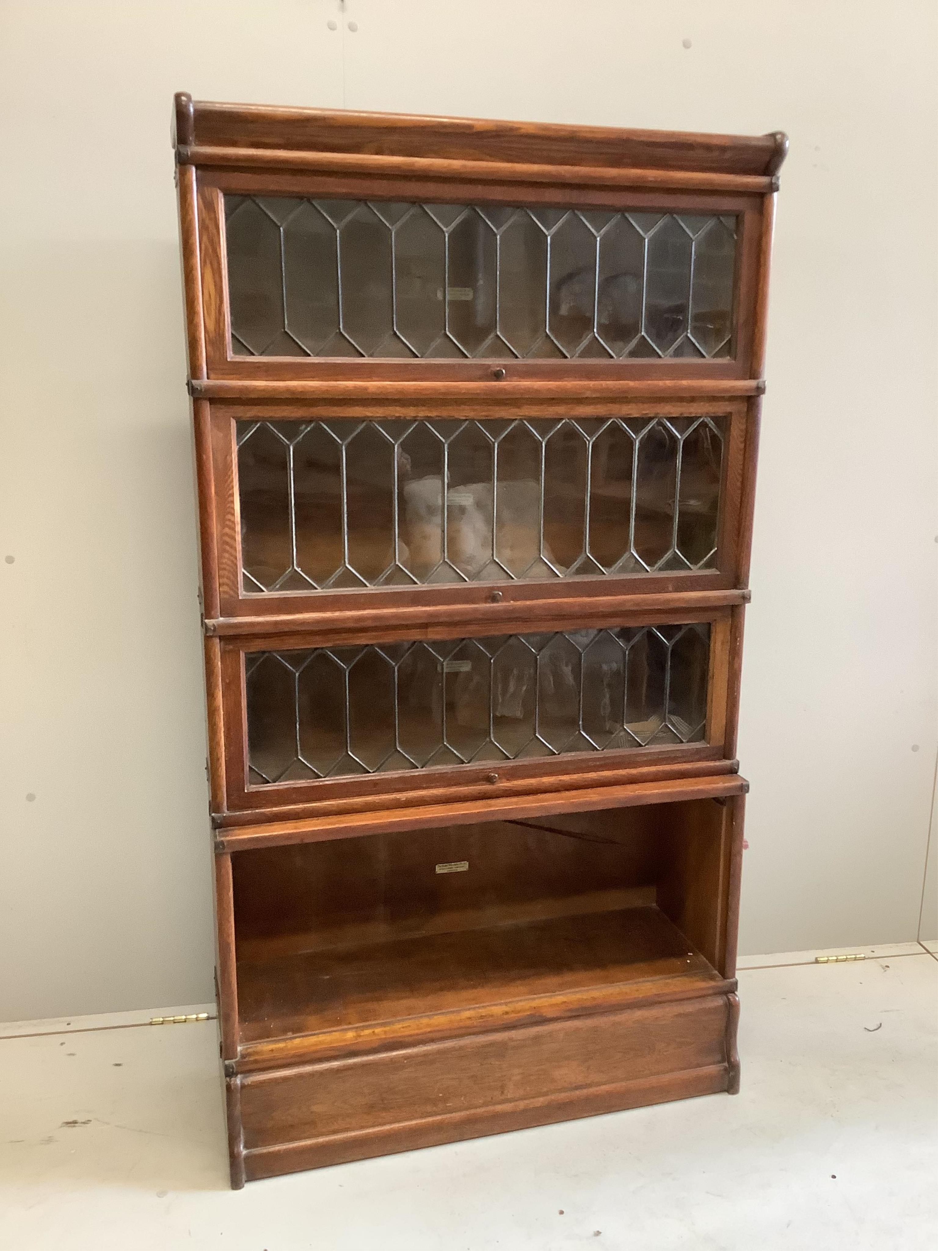 An early 20th century Globe Wernicke oak four section bookcase, one door of lower section extensively damaged, width 86cm, depth 29cm, height 156cm. Condition - fair